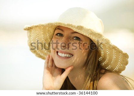 Beautiful young woman with the hat smiling on the beach. Perfect smile