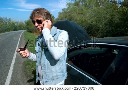Businessman on a mobile phone in front of a broken car