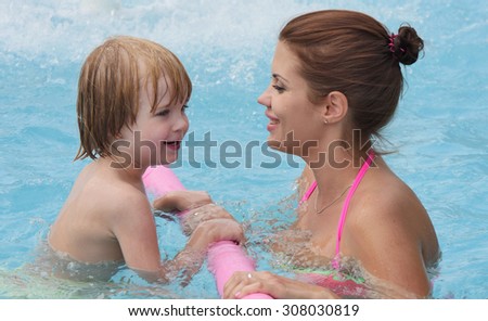 small child learns to swim in the pool with his mother