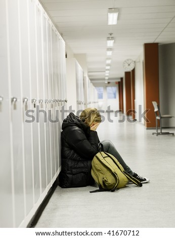 Young woman crying by the lockers at school