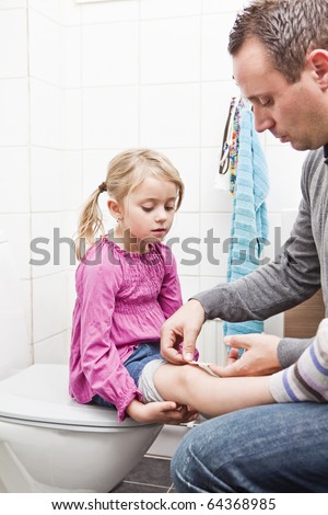 Father put on band-aid on daughters knee