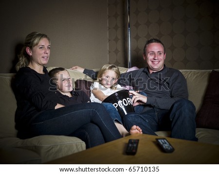 Family in front of the Television sitting in a sofa