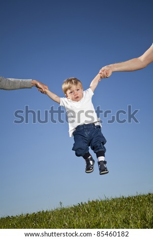 Child hanging in the air between parents hands