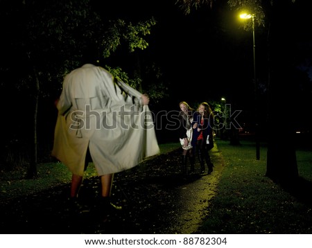 Two women laughing at a Flasher at night in the park