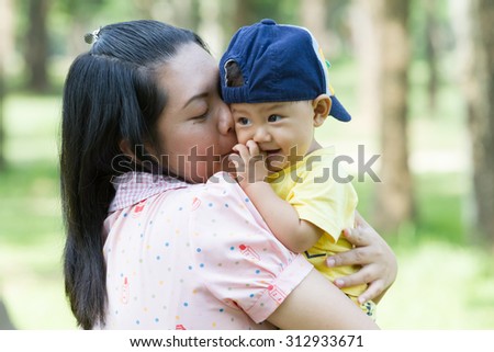 mother hug hold and kiss son in park with love and happy