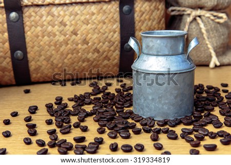 Zinc pot with coffee bean on wooden table and hamper basket and sack background