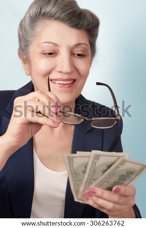Portrait of an elderly woman looking at the money through the glasses