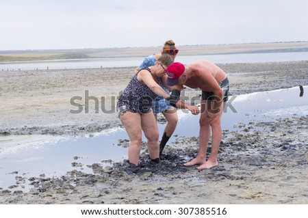 NOVOROSSIYSK, RUSSIA - 04 JULY, 2015: The woman rubs a hand man curative mud on the Azov Sea