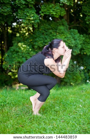 woman in black making yoga asana - eagle pose