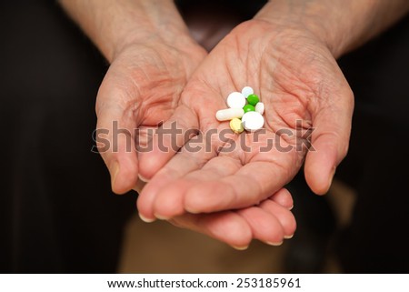 old man\'s palm with multicolored pills and vitamins