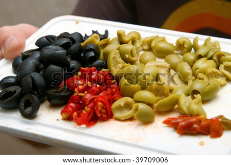 closeup plate with cut green and black olives and hot pepper