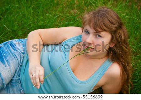 portrait of a beautiful female lying on a grass, it is summer and she is holding a blade of grass