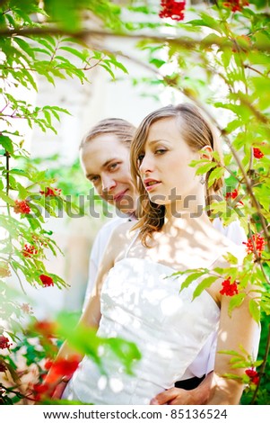 portrait of a bride and groom standing near the tree with red berries