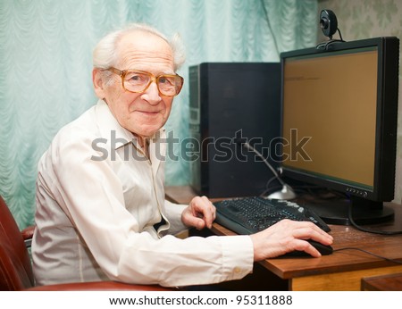 smiling happy old man sitting near computer and holding mouse