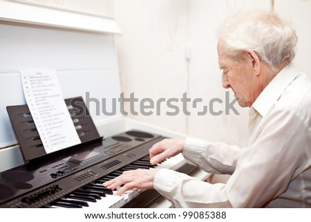 grey-haired senior man playing piano