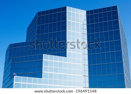 A geometric building made of glass panes under a blue sky.