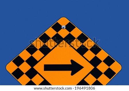 Street sign bordered with racetrack like checkered squares and a directional arrow in the center.