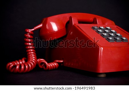 A retro, pillar box red telephone sits on the black counter.