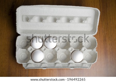 An open egg carton with only four eggs in it.