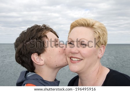 A boy kissing a lady on the cheek.