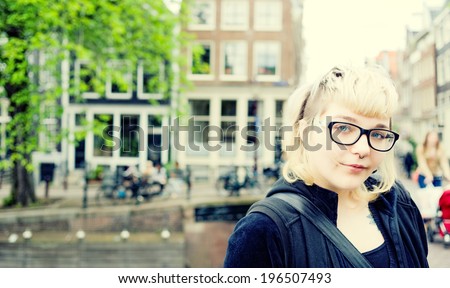 A lady with dark rimmed glasses in a city.