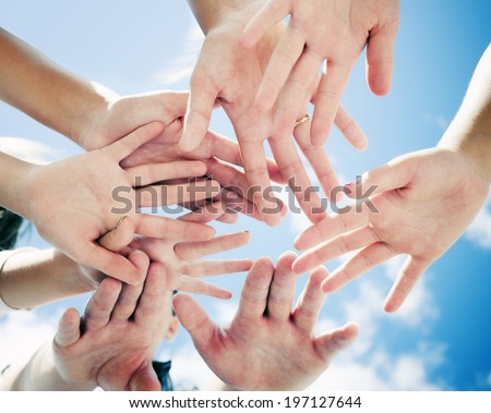 A group of people with their hands all in the middle.