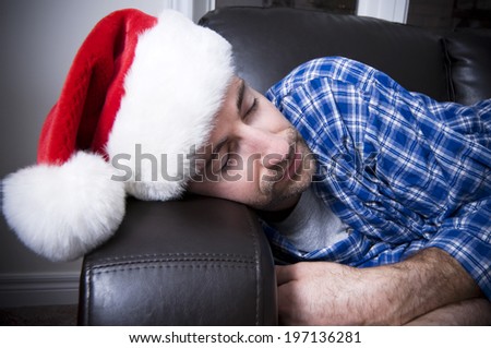 A close-up of a man in a Santa hat sleeping.