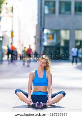 A woman sits on the sidewalk dressed in fitness gear.