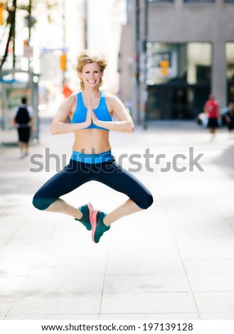 A lady doing exercises outside as she jumps in the air.