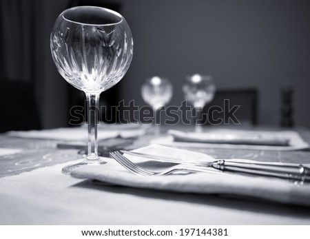 Silverware, napkins and crystal glasses are laid on a dinner table.