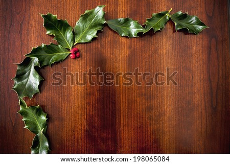 Holly leaves and berries on a wooden table.
