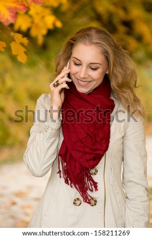 Happy young woman on cell phone in autumn park