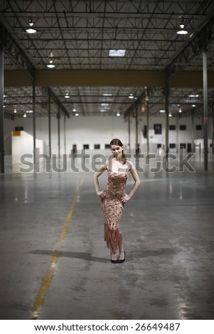 A woman wearing a pretty dress in a warehouse.