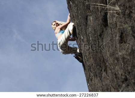A sexy young woman climbing a stone wall