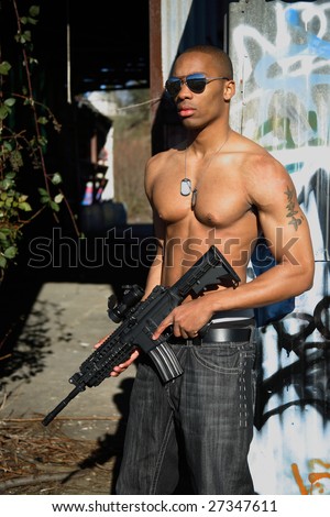 A fit young man with an assault gun.