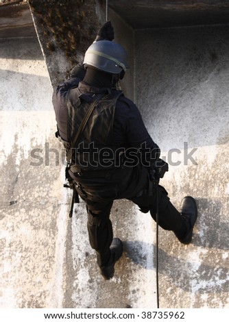 Officer in full tactical gear with weapons climbing down a rope.