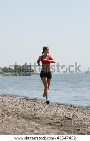 Athletic woman running next to a river.