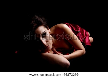 Beautiful woman covered in red satin sheet.