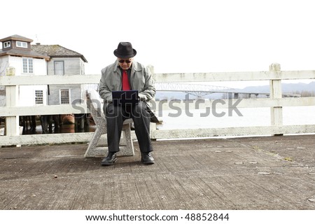 Man using laptop on the pier.