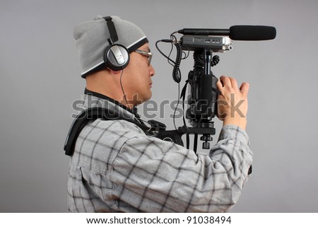 Man shooting video with a digital SLR camera with shotgun microphone and separate audio recorder.