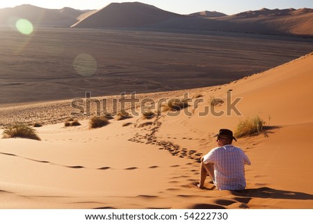 Man watching the sun go down on a sand dune