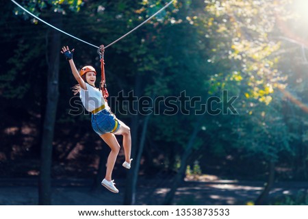 Happy women girl female gliding climbing in extreme road trolley zipline in forest on carabiner safety link on tree to tree top rope adventure park. Family weekend children kids activities concept Stock foto © 