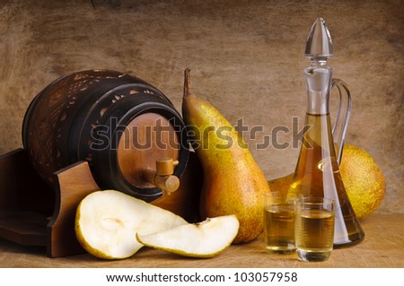glasses and bottle of traditional fruit brandy with pear fruits and barrel on a wooden background
