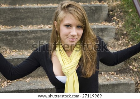 Attractive Teenage Girl kneels down in front of cement stairs staring into the camera with a self-assured glance vulnerable