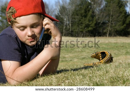 A young boy takes a break from baseball practice to chat on a cellular telephone