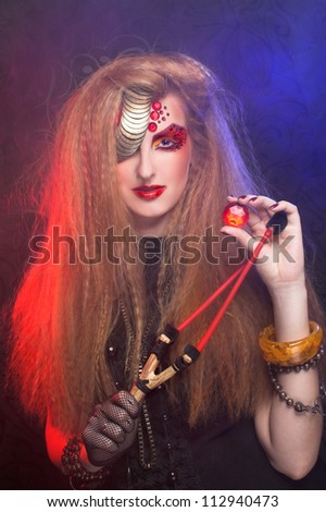 Young woman in artistic image with one-eyed visage posing with smoke