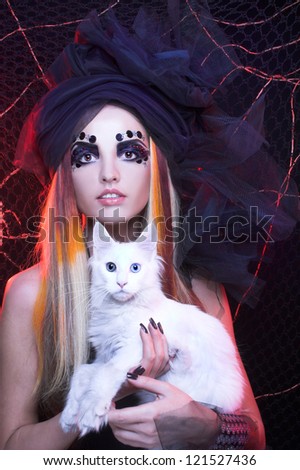 Gothic lady with artistic makeup posing witt white cat