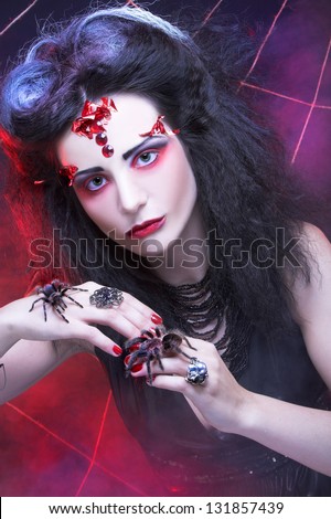 Black widow. Young woman in dark artistic image posing with spider