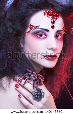Black widow. Young woman in dark artistic image posing with spider