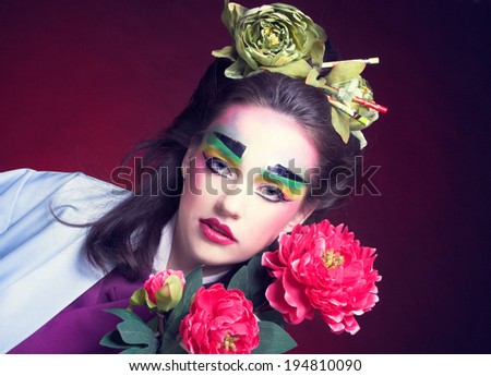 Young woman in creative image in eastern style with flowers in hair and in kimono.